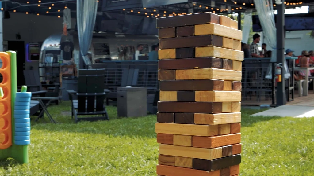 Giant Jenga on grass at outdoor restaurant with Airstream trailer.