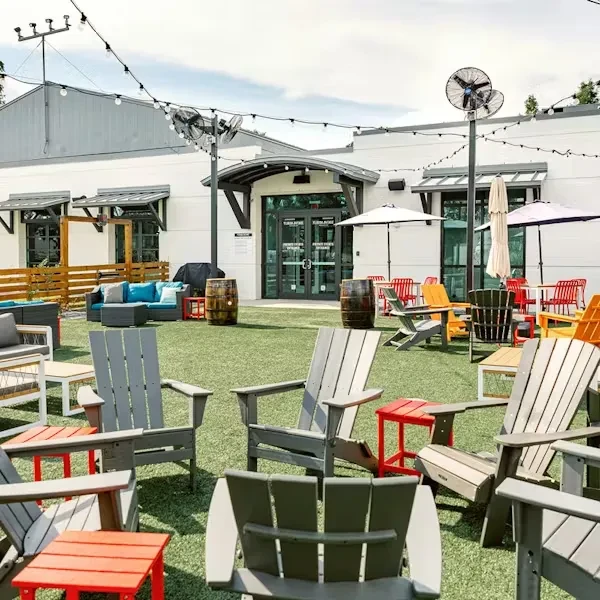 Bright outdoor restaurant patio with varied seating under umbrellas.