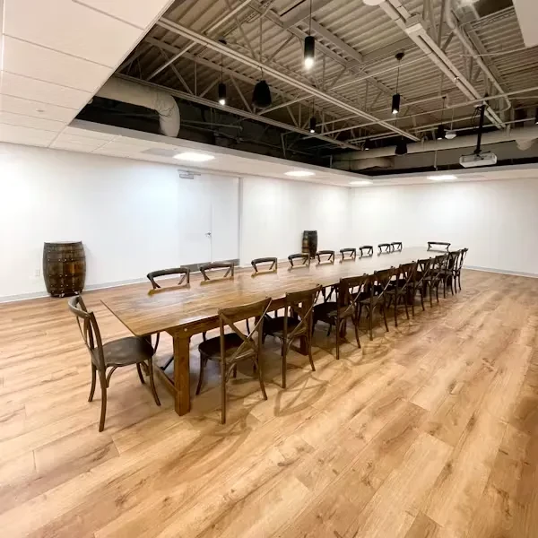 Modern event space with a long rustic dining table and industrial ceiling.