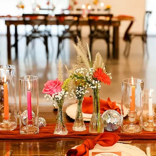 Decorated dining table with rose, gerbera, candles, disco ball, and menu.
