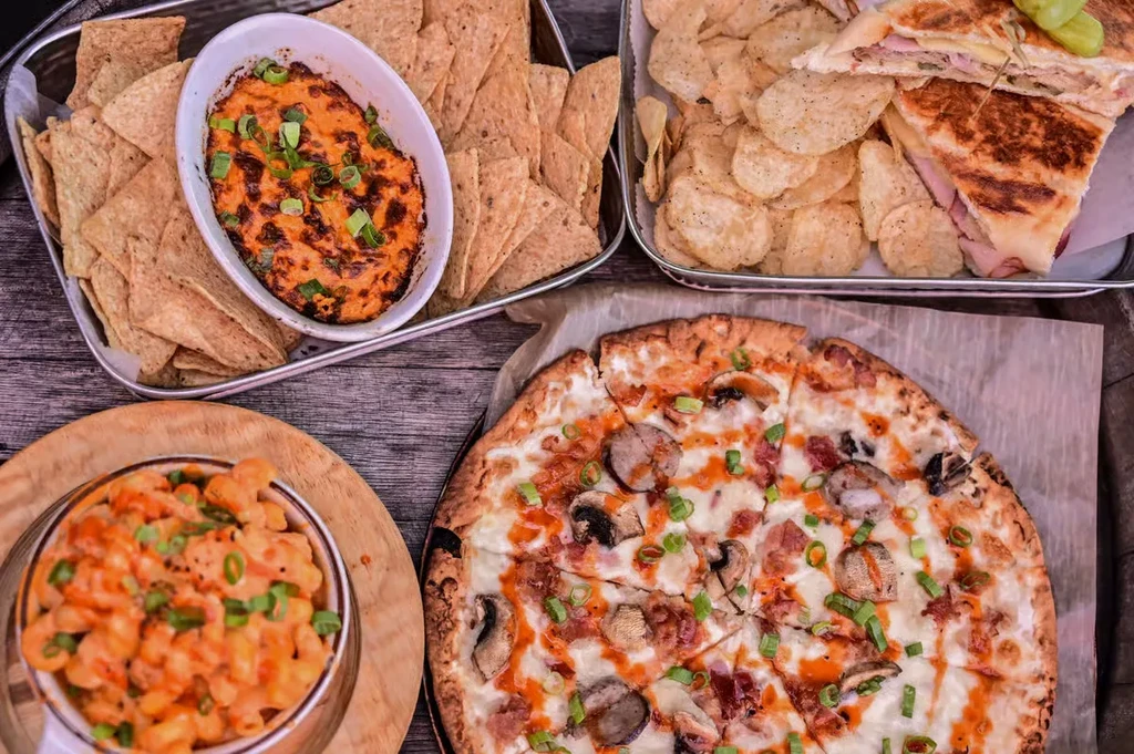 Overhead view of dip, chips, panini, pizza, and macaroni and cheese.
