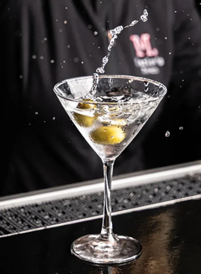Martini glass with olives and a dynamic splash of liquid.