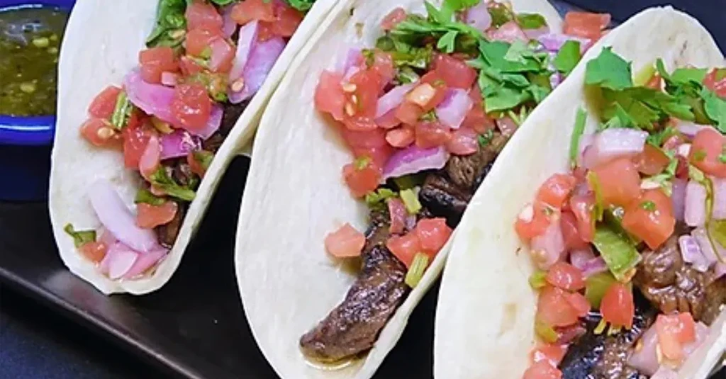 Three grilled meat tacos, pico de gallo, and salsa verde.