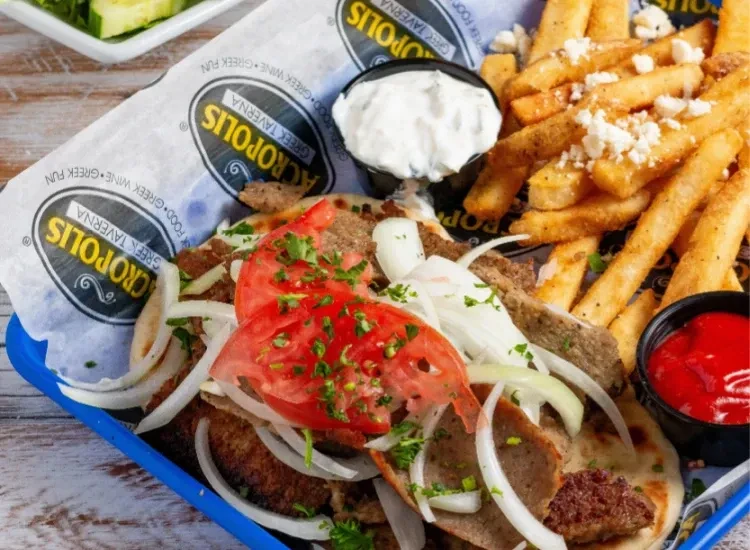 Greek gyro platter with meat, fries, sauces, and restaurant branding.