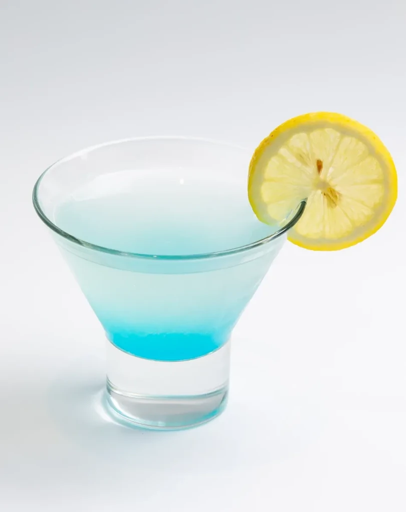 Vibrant blue gradient cocktail in a martini glass with a lemon slice.