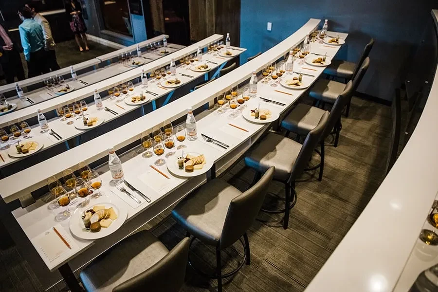 Elevated tables with glasses of amber liquid set for a tasting event.