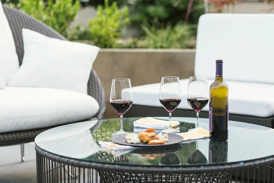 Outdoor table set with red wine, cheese, and appetizers.