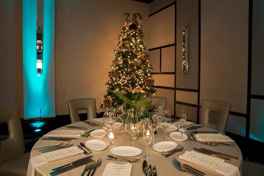 Restaurant dining table set for Christmas, with a decorated tree.