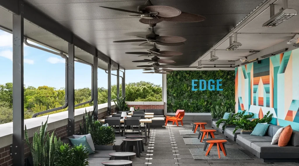 Modern outdoor patio featuring sofas, green living wall, and geometric mural.