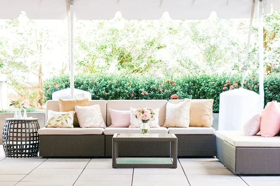 Outdoor patio with dark brown woven sofas, beige cushions, rose bouquet.