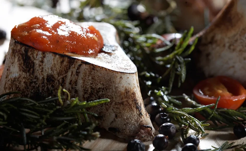Roasted bone marrow, cut lengthwise, with red relish and herbs.