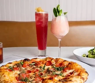 Restaurant table with pepperoni pizza, two drinks, and a green salad.