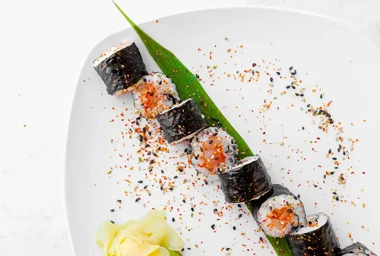 Seven maki sushi rolls with tuna, sesame, green leaf, and ginger.
