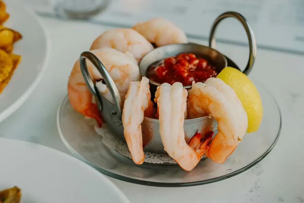 Shrimp cocktail appetizer with red sauce, plump shrimp, and lemon.