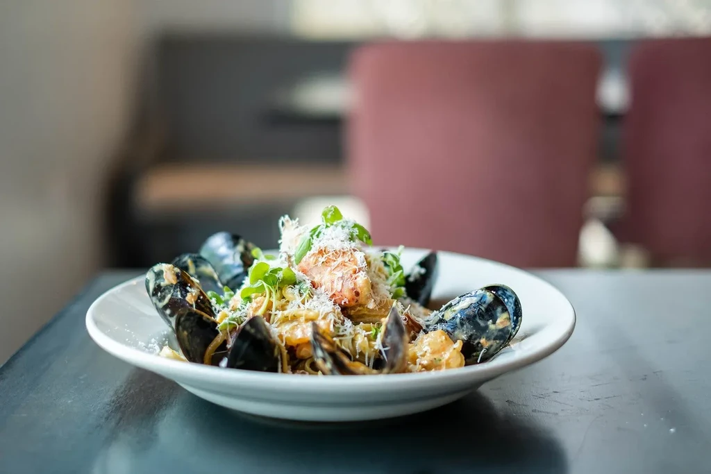 Close-up of creamy seafood pasta with mussels, cheese, and fresh herbs.