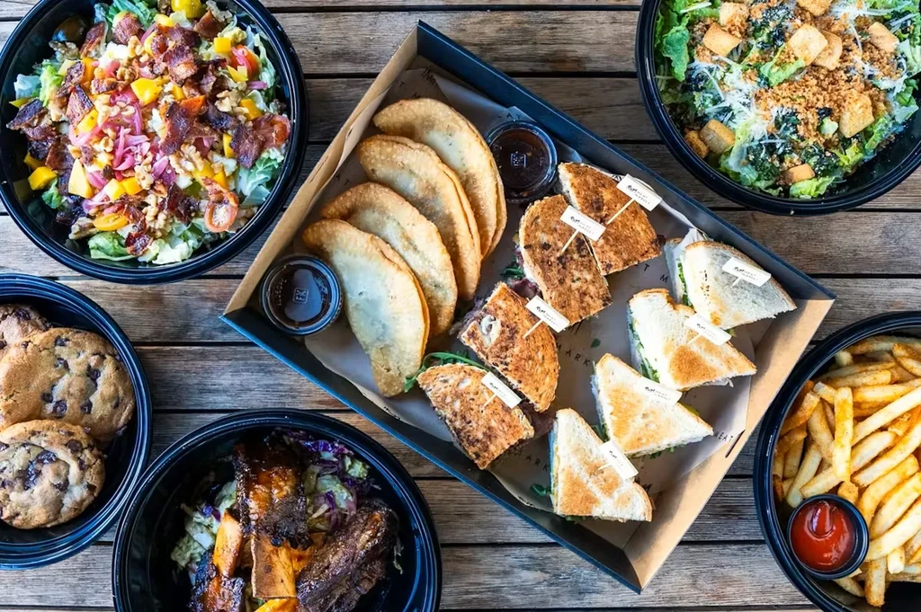 Diverse takeout and catering food displayed on a rustic wooden table.