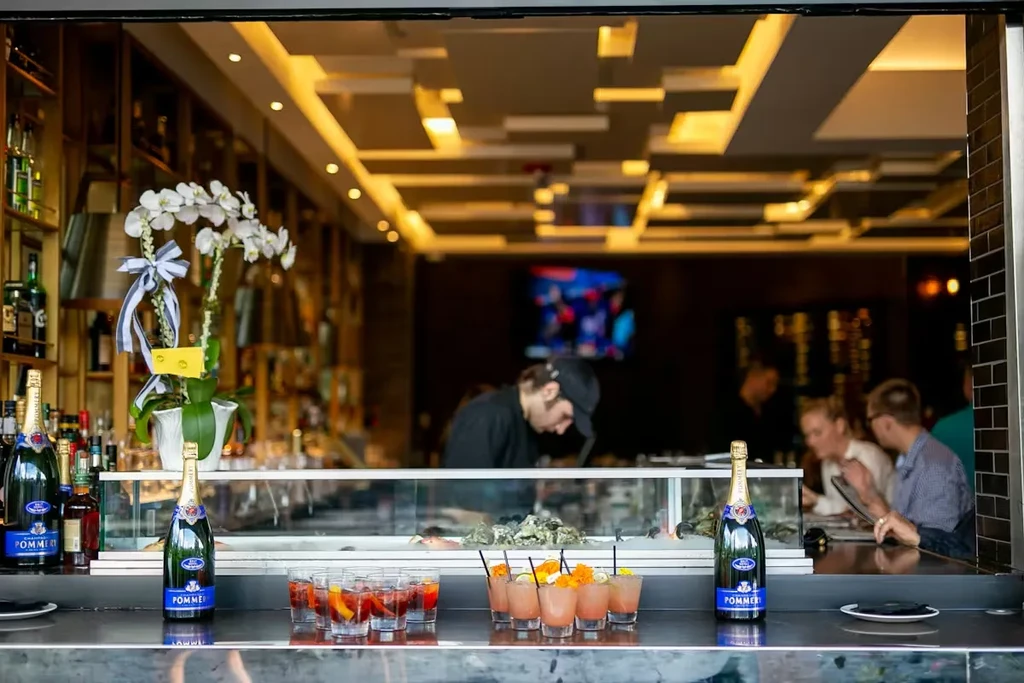 Two champagne bottles frame vibrant cocktails on an upscale bar counter.
