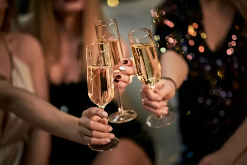 Close-up of three hands holding champagne flutes at a celebration.