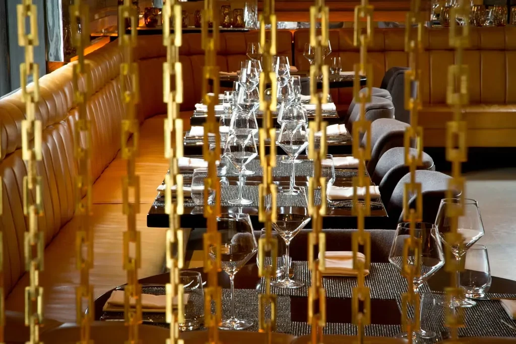 Elegant restaurant dining area with golden dividers, set tables, and banquette.
