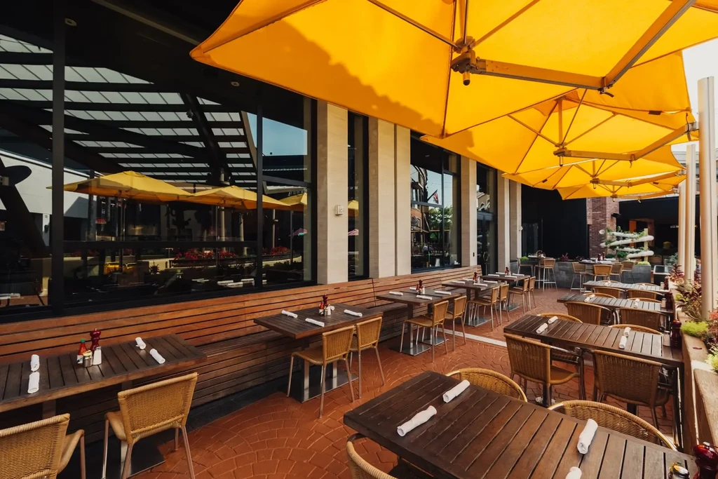 Empty outdoor restaurant patio with bright yellow umbrellas.