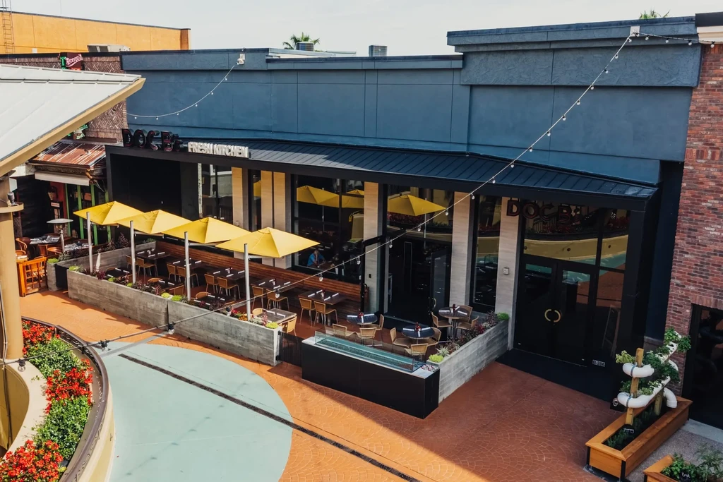 Modern Doggy Fresh Kitchen restaurant with spacious patio and yellow umbrellas.