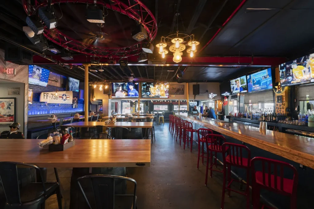 Lively industrial bar/restaurant with military decor, screens, and gear chandeliers.