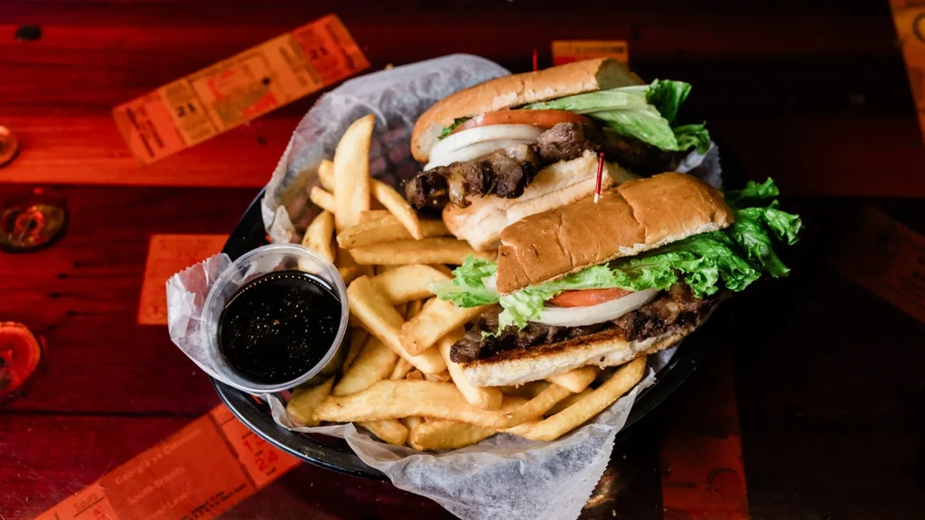 Overhead shot of a grilled sandwich with fries and dipping sauce.