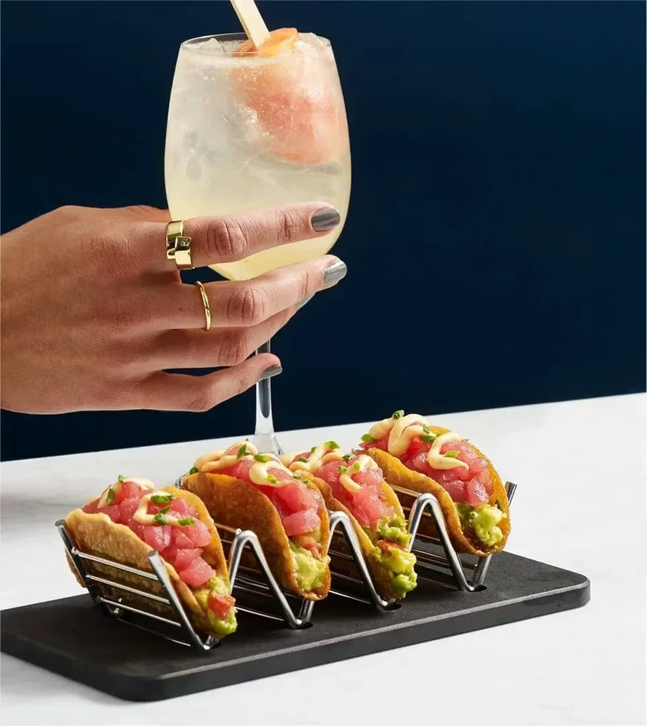 Four crispy tacos with red fish and a stemmed yellow cocktail.