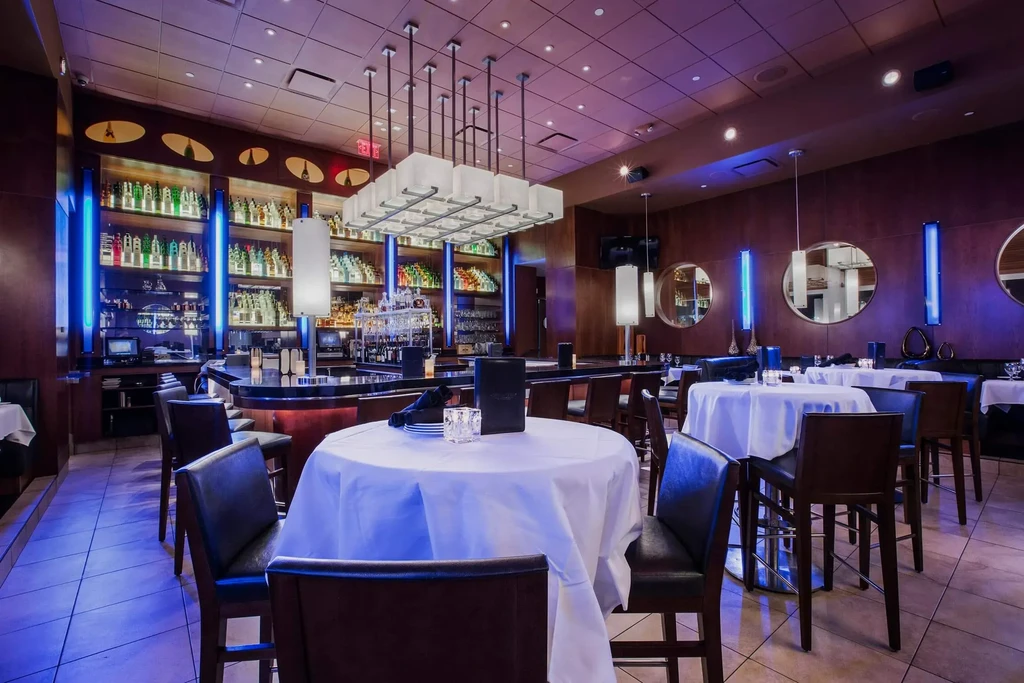 Upscale restaurant interior with a vibrant blue-lit bar and dining area.