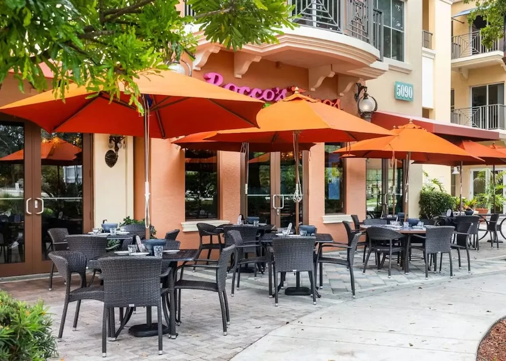 Empty Rocco's Tacos patio with wicker furniture and orange umbrellas.