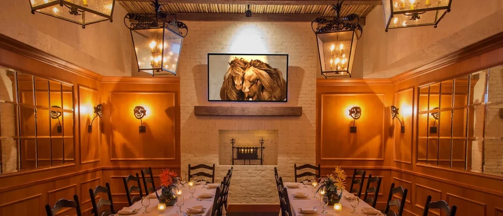 Private dining room with wood, brick walls, fireplace, and set table.