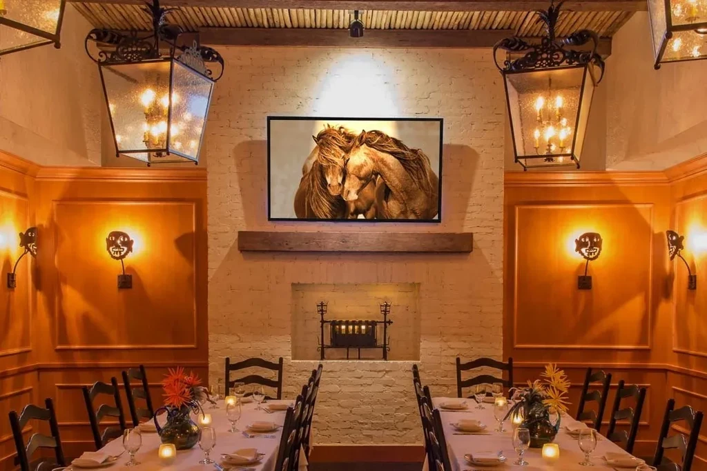 Warmly lit restaurant dining room featuring two elegantly set long tables.