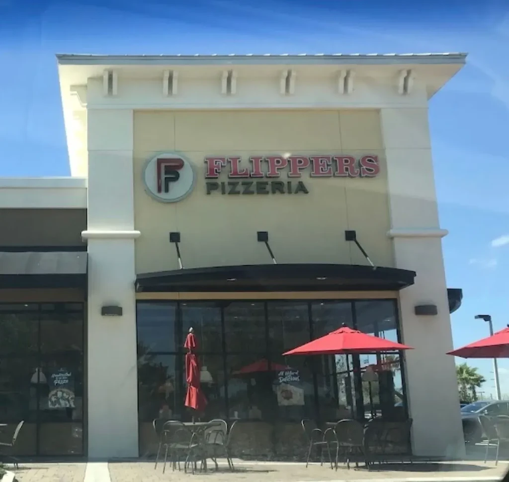 Flippers Pizzeria: Modern exterior with red sign and red-umbrella patio.