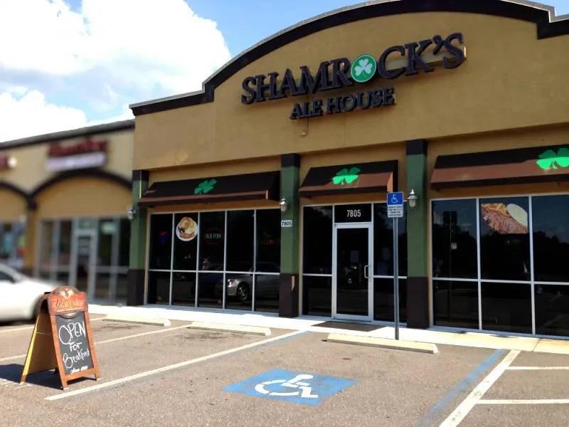 Sunny exterior of Shamrock's Ale House, showing food and breakfast signs.