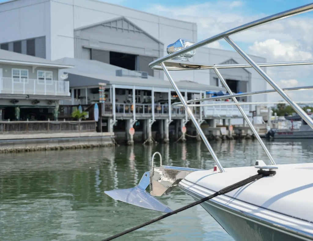 White boat bow, sunny waterfront with buildings and industrial structure.