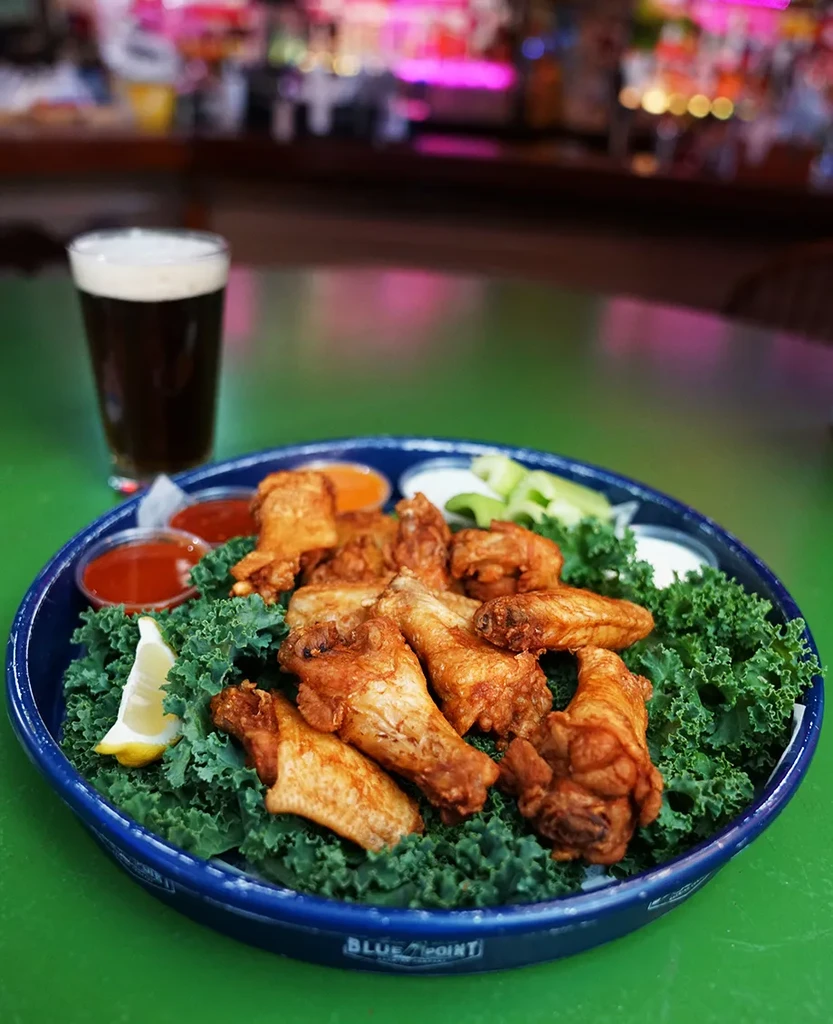 Golden fried chicken wings, kale, dipping sauces, and dark beer.