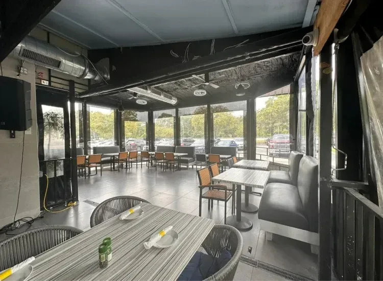 Empty modern restaurant dining room, industrial-chic with natural light and booths.