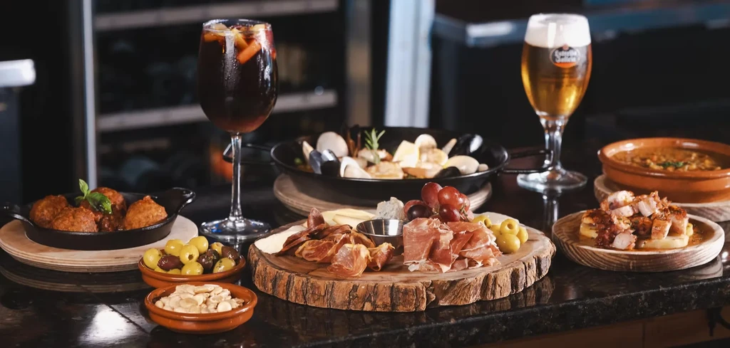 Spanish-style food spread with charcuterie, tapas, beer, and sangria.