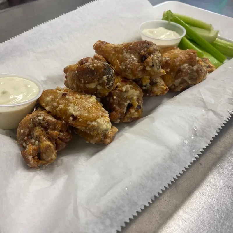 Light-sauced chicken wings, two white dipping sauces, and celery stalks.
