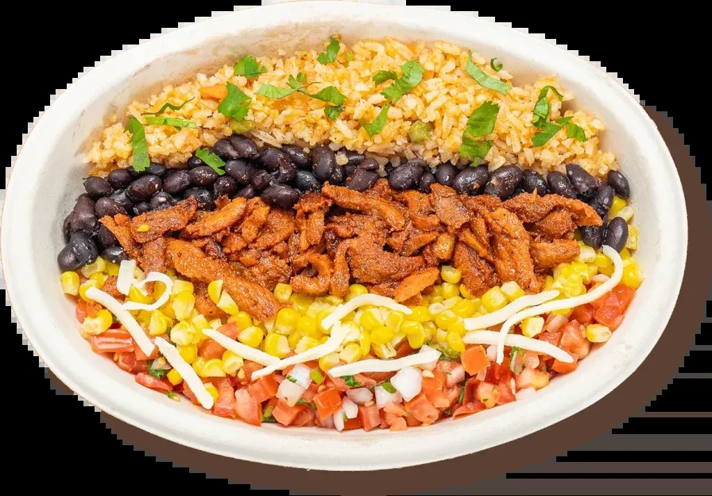 Colorful layered burrito bowl with seasoned rice, beans, chicken, and vegetables.