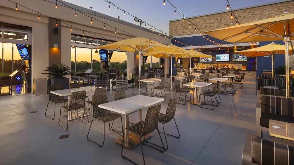 Empty Topgolf outdoor bar, dining, and golf bays at golden hour.