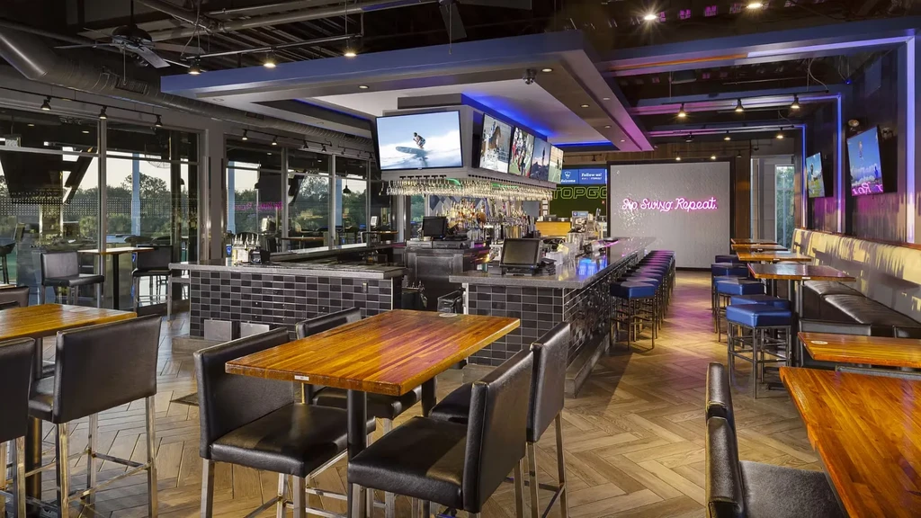 Modern bar and restaurant interior with long bar, dining, and sports TVs.
