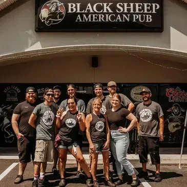 Ten smiling staff members in front of Black Sheep American Pub.
