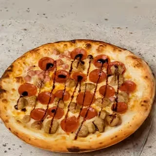 Whole pizza with pepperoni, sausage, ham, drizzled with balsamic glaze.