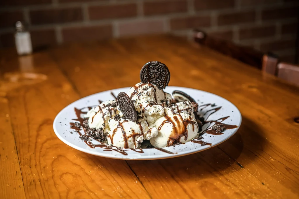 Vanilla ice cream with chocolate sauce and upright sandwich cookies.