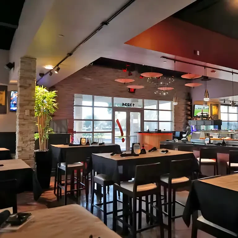 Modern restaurant interior with high-top tables, stone, bamboo, and umbrella lights.
