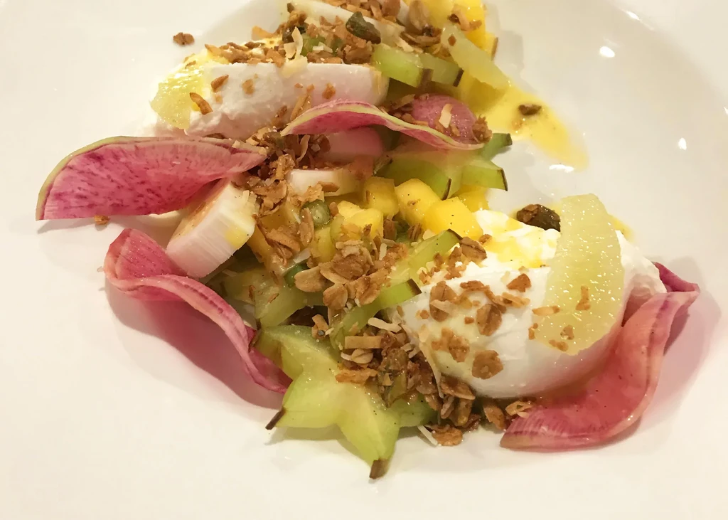 Vibrant fruit salad with creamy dollops, star fruit, radish, and granola.