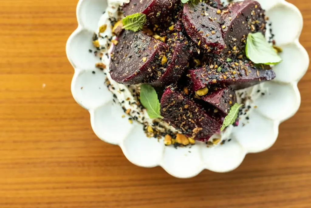 Overhead shot of spiced beets, pistachios, and mint on creamy base.
