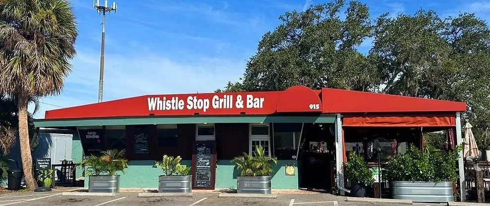 Whistle Stop Grill & Bar exterior with red roof and outdoor patio.