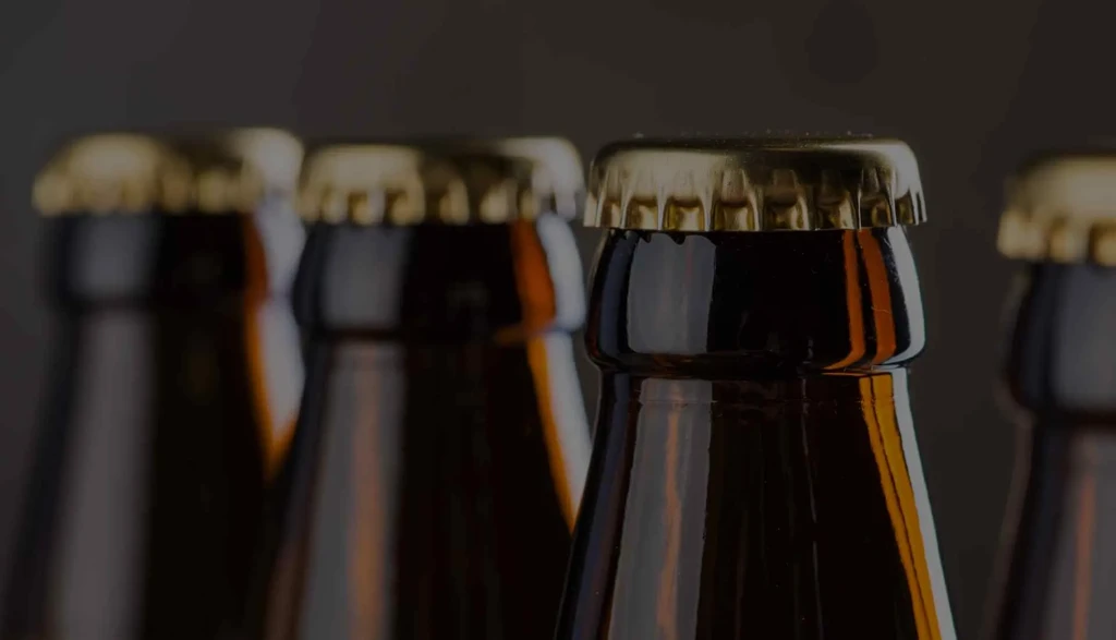 Row of dark glass bottles, one with golden cap in sharp focus.